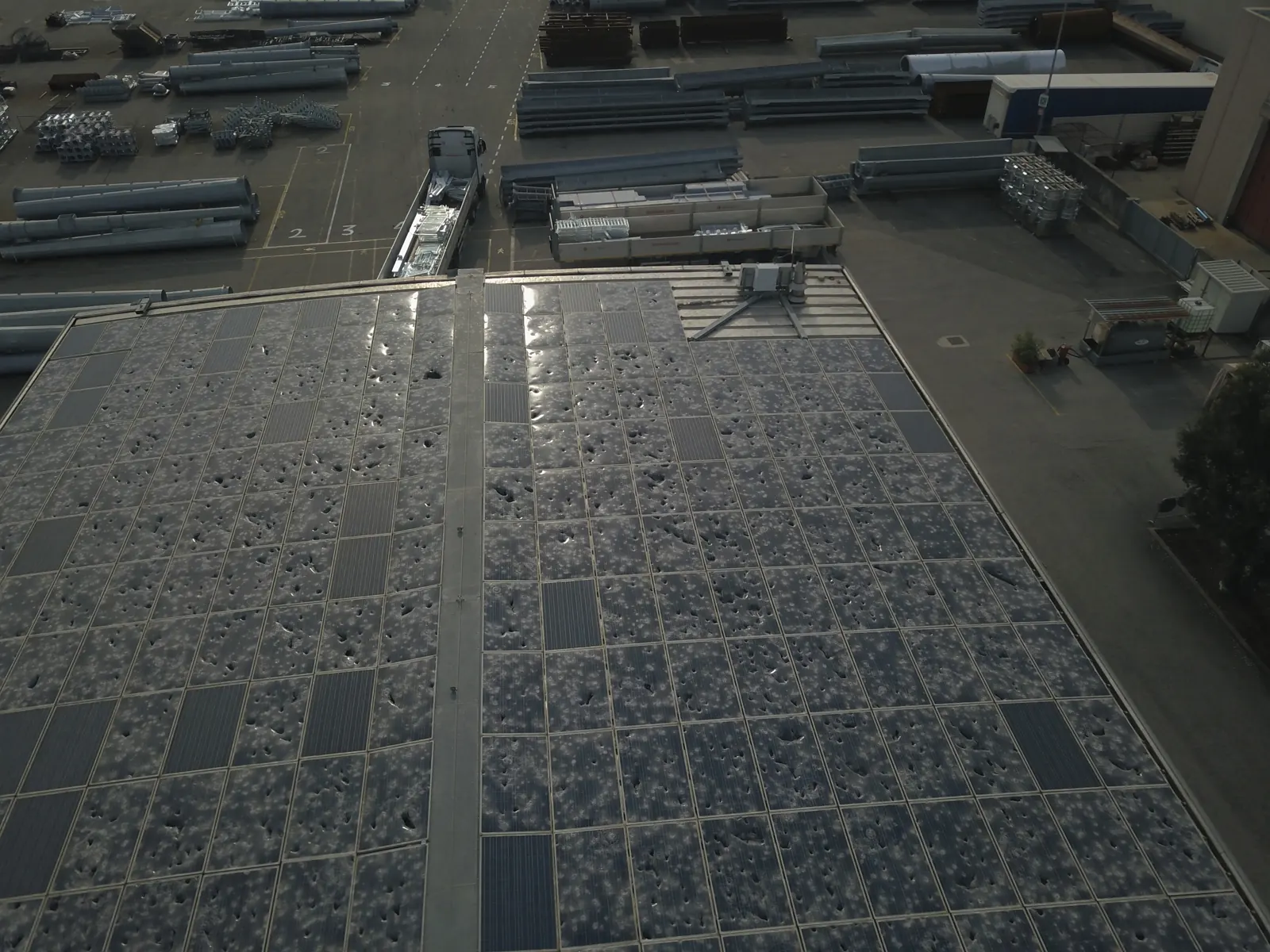 Un grande impianto fotovoltaico sul tetto di un capannone colpito dalla grandine, visto dal drone