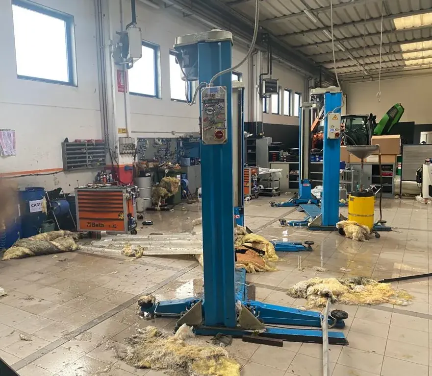 L'interno di un'officina con isolante e acqua sul pavimento dopo che il vento ha scoperchiato il tetto