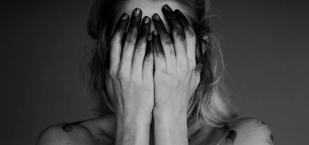 Una donna si copre il volto con le mani annerite dalla fuliggine
